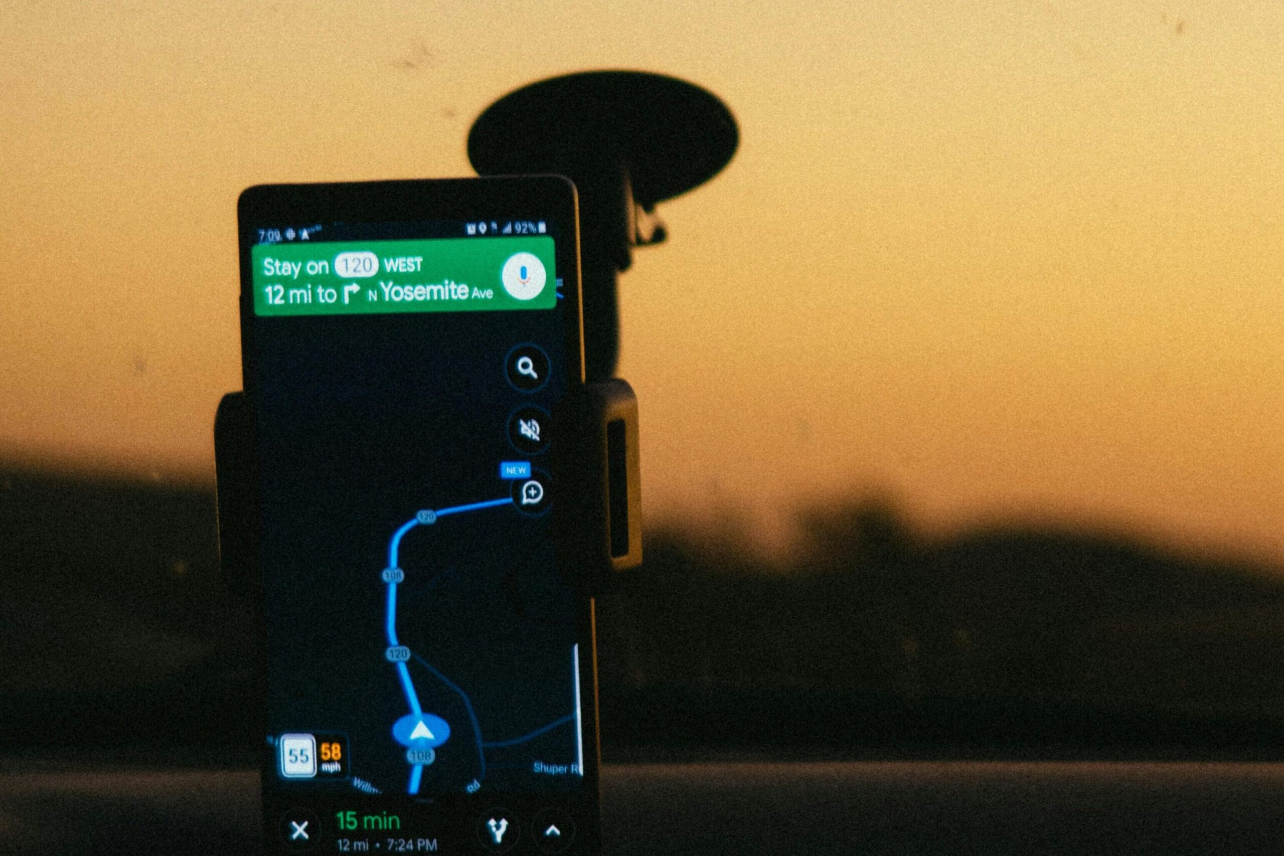 Smartphone GPS navigation held in a car during a picturesque sunset drive. Ideal tech travel imagery.